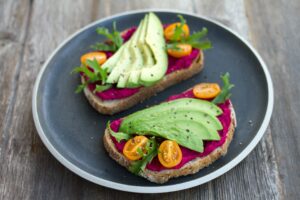 Dish with two toasts with avocado, rocket and cherry tomatoes