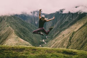 Woman jumping full of energy with mountains in the background