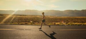 A person running along a road in shorts without t-shirt